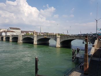 Arch bridge over river against sky in city