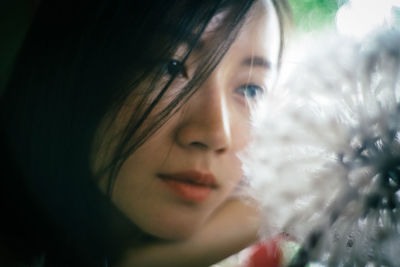 Close-up of woman looking at dandelion