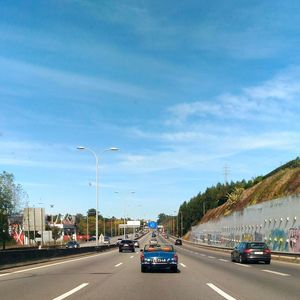 Vehicles on highway against sky in city