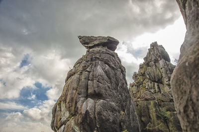 Low angle view of statue against rock formation against sky