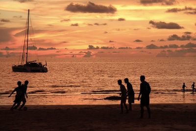 Silhouette people on beach against sky during sunset