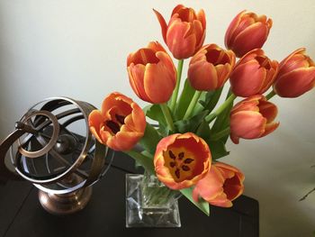 High angle view of tulips in vase by decor on table against wall at home