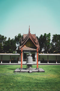 Gazebo on field by building against clear sky