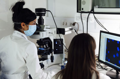 Female scientists working together while examining medical samples on computer in laboratory during covid-19