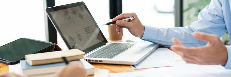 Midsection of businessman pointing at laptop screen at desk