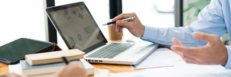 Midsection of businessman pointing at laptop screen at desk