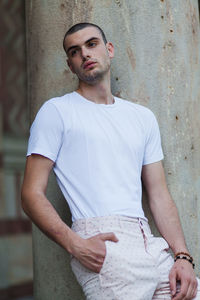 Portrait of young man standing against wall