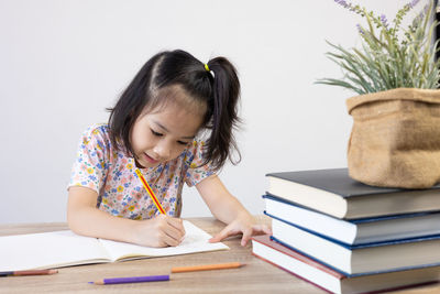 Side view of girl playing with books on table