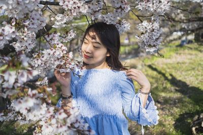 Beautiful woman standing by cherry blossom tree