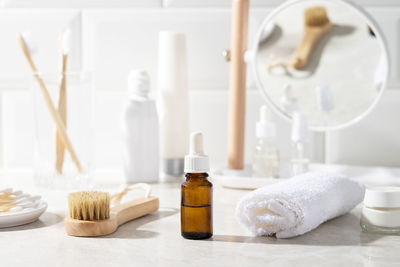 Massage oil or facial serum in a glass bottle in the bathroom. white towel, cream, toothbrushes.