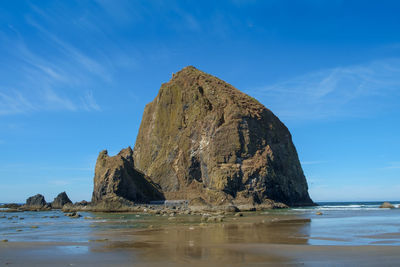 Rock formation by sea against blue sky