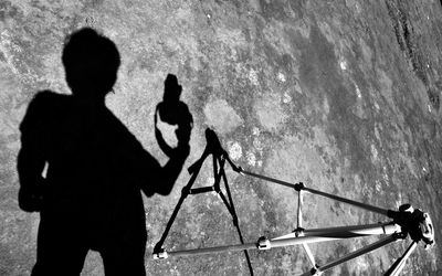 Shadow on man with camera standing by tripod