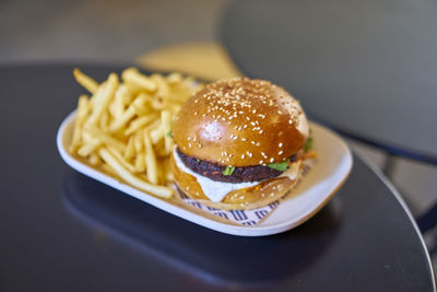 High angle view of burger with french fries in plate on table