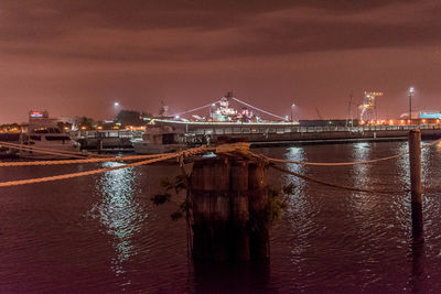 Illuminated city by sea against sky at night