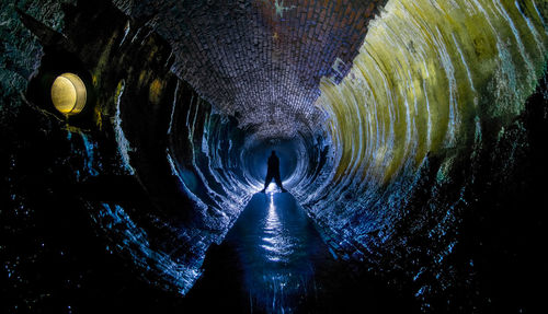 Rear view of person standing in illuminated tunnel