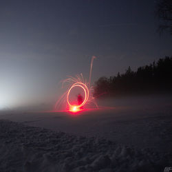 Light trails on field against sky at night