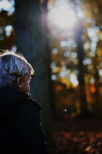 Boy standing against trees during autumn