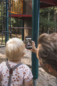 Rear view of woman photographing with mobile phone