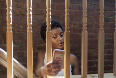 Young woman taking a selfie through a banister