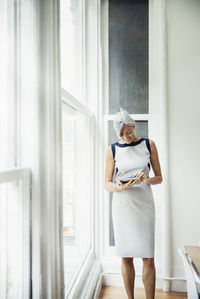 Happy businesswoman using tablet computer by window in creative office