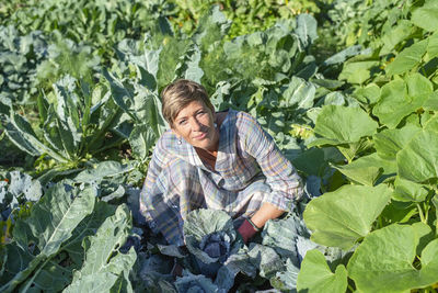 Portrait of young woman standing amidst plants