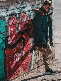 Young man standing against graffiti wall