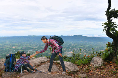 Woman with arms raised on mountain against sky