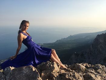 Woman standing on rock against sky