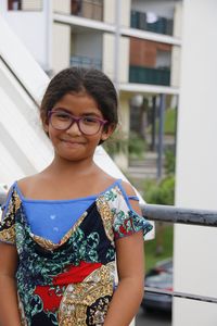 Portrait of smiling girl wearing eyeglasses while standing against building in city