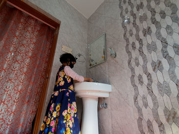 Rear view of woman standing against wall in building