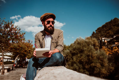 Man writing in book while sitting outdoors