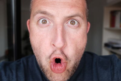 Close-up portrait of shocked man at home