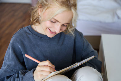 Portrait of young woman writing in book