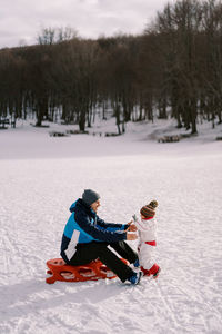 Rear view of woman skiing on snow covered field