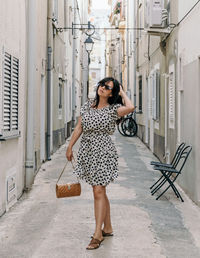 Portrait of attractive young woman standing in alley. summer dress, style, lifestyle.