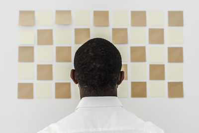 Man looking at adhesive notes on wall in office