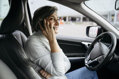 Woman talking on smart phone while sitting in car