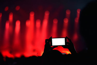 Close-up of hand photographing with smart phone during concert