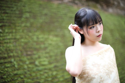 Young woman looking away while standing outdoors