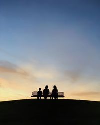 Silhouette of people on landscape at sunset