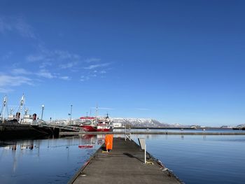 Boats moored at harbor against blue sky