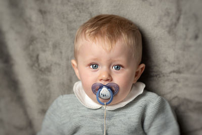 Close-up portrait of cute baby boy with pacifier in mouth