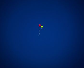 Low angle view of balloons against clear blue sky