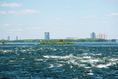 Sea and buildings in city against sky