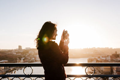 Woman in porto bridge taking pictures with camera at sunset. tourism in city europe. travel