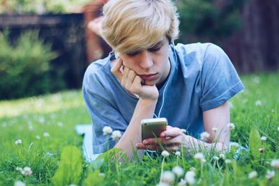 Young woman using mobile phone while sitting on grass