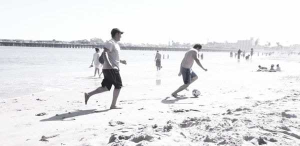 People walking on beach against clear sky