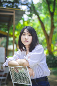 Portrait of young woman standing against tree