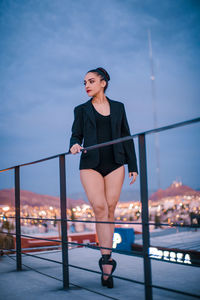 Portrait of woman standing by railing against sky