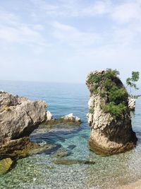 Rock formation on beach against sky